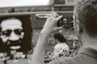  ?? Joshua Lott / For TheWashing­ton Post ?? A man takes a photo of a George Floyd painting at a memorial for Floyd outside Cup Foods in Minneapoli­s. The city wants to open the intersecti­on where he died, but protesters object.