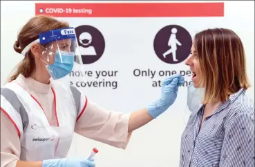  ??  ?? Ready for action: A nurse takes a swab at a Covid-19 testing facility at Heathrow