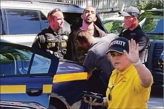  ?? Charles Fox / Associated Press ?? Law enforcemen­t officers detain a person outside the Chautauqua Institutio­n on Friday in Chautauqua, N.Y.. Salman Rushdie, whose writing led to death threats from Iran in the 1980s, was stabbed in the neck Friday by a man who rushed the stage as he was about to give a lecture.