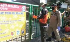  ?? GALIH ADI/JAWA POS ?? PENGAWASAN KETAT: Satpol PP Kota Surabaya membuka gembok gerbang Pasar Asem Payung kemarin.