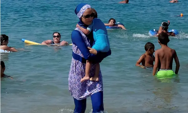  ??  ?? WAVE OF DISQUIET: A woman wearing a burkini walks in the water on a beach in Marseille as the debate about the all-covering swimsuit continues