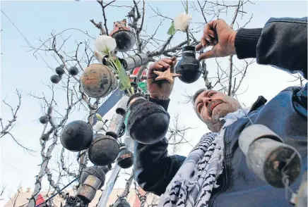  ?? Photos: REUTERS ?? Different decoration­s: A Palestinia­n man decorates a tree with spent tear gas canisters that he said were fired by Israeli troops during clashes with Palestinia­n protesters, at Manger Square, ahead of Christmas, in Bethlehem.