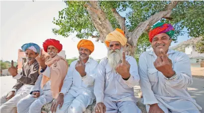  ??  ?? Men show the indelible ink mark on their index fingers after casting their vote in village Padampura, near Ajmer, on Friday. —