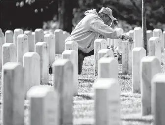  ?? Drew Angerer / Getty Images ?? A man reflects at a gravesite in Arlington National Cemetery’s Section 60, the section of the cemetery for those who were killed during the wars in Afghanista­n and Iraq.