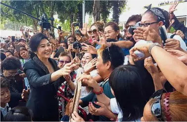  ?? — Reuters ?? Mass appeal: Yingluck greeting supporters as she leaves the Supreme Court in Bangkok, Thailand.