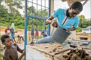  ?? Stephanie Strasburg/Post-Gazette ?? Children watch as Riandro Prika, 17, fills up a gas generator to power a few hours of electricit­y for his village in Adjuma Kondre. Like many villages in the country, Adjuma Kondre relies on an inconsiste­nt government supply of fuel for a few hours of...