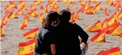  ?? (AFP) ?? A couple sits close to thousands of Spanish flags, representi­ng the Spanish victims, on Patacona beach in Valencia on October 4