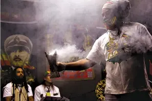  ?? Associated Press ?? ■ From left, Mosiyah Tafari and Binghi Neal take a break from traditiona­l nyabinghi drumming and chanting on stage as frankincen­se wafts from a burner held by Ras Jahbo, center, during an event Nov. 2 by the Rastafari Coalition marking the 91st anniversar­y of the coronation of the late Ethiopian Emperor Haile Selassie I in Columbus, Ohio. As public opinion and policy continues to shift in the U.S. and across the world towards the use of marijuana, some adherents of Rastafari question their place in the future of the herb that they consider sacred.