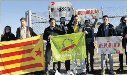  ??  ?? > Supporters of the jailed Catalan independen­ce leaders stand with an independen­ce flag and banners reading ‘republic’, ‘repression’ and ‘democracy’ while waiting for the release of Catalan politician­s in Spain yesterday