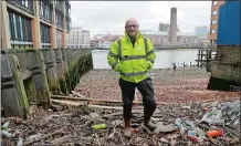  ?? MATT DUNHAM/AP PHOTO ?? Volunteer Michael Byrne poses for photograph­s beside plastic bottles washed up at the Queenhithe dock.