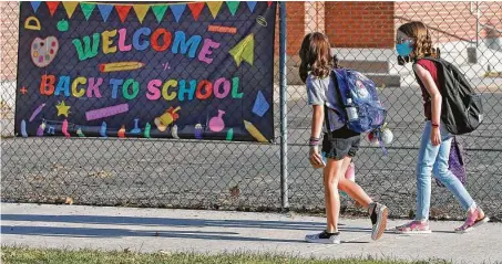  ?? Rick Bowmer / Associated Press ?? Cimmie Hunter, left, and Cadence Ludlow, both sixth-graders, arrive at Liberty Elementary School on Monday in Murray, Utah. Murray City School District offered its students a choice among in-person learning, hybrid instructio­n and distance learning.