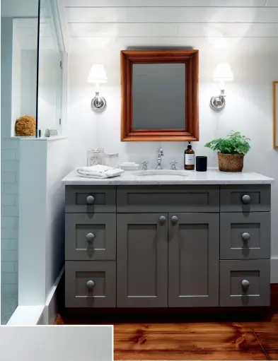  ??  ?? ABOVE: The main bathroom’s vanity, a big-box store find, was given country charm with wooden knobs and a coat of grey paint. Vanity, Rona; vanity colour, Elephant Skin (PPU18-16), Behr.
TOP LEFT: The black lacquered tulip table is Michael’s own design, inspired by the Art Deco period.
BOTTOM LEFT: With a palette of navy and brown pulled from the antique rug, the twin guest room has a clubby feel. The velvet-upholstere­d beds are paired with an antique English chest and glossy black–shaded lamps. Bed linens, Au Lit Fine Linens; chest, Land & Ross Antiques.