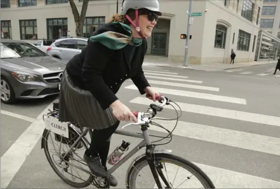  ?? PHOTOS BY STEVEN SENNE, THE ASSOCIATED PRESS ?? Rev. Laura Everett, executive director of the Massachuse­tts Council of Churches, rides her bike to a meeting. She has written a book about her two-wheeled experience­s.