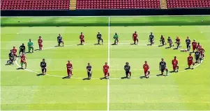  ??  ?? Liverpool players take a knee at the centre circle of Anfield.