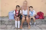  ??  ?? Siblings Melissa and Yonkiel sit with their “abuela” (grandmothe­r) in a quiet corner of the town square of the colonial town of Remedios.