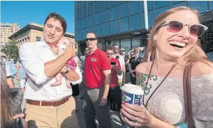  ?? THE CANADIAN PRESS FILE PHOTO ?? Liberal Leader Justin Trudeau holds baby Adalyn Hayes while Erika Golem laughs at the Regina Farmers' Market during the 2015 federal election campaign. Kissing babies is somewhat less fashionabl­e than it once was, but photos with babies are definitely still a thing on the campaign trail, Susan Delacourt writes.