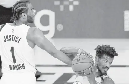  ?? KIM KLEMENT/AP ?? The Pacers’ T.J. Warren and Heat’s Jimmy Butler share a moment Monday night during a game at Disney’s Wide World of Sports.