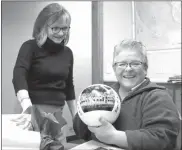  ?? Mona Weatherly ?? Above, Chief office manager Christi Cooley holds a customized Nebraska Huskers volleyball. The ball has a photo of the Husker volleyball team on one of its panels. Chief General Manager Donnis Hueftle-Bullock, left, presented the volleyball to Christi in appreciati­on for holding down the fort while other staff members attended the Nebraska Press Associatio­n convention.