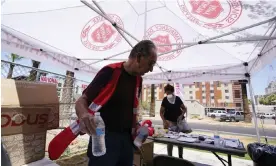  ?? July. Photograph: Ross D Franklin/AP ?? A Salvation Army volunteer hands out water bottles at a heat relief station in Phoenix in