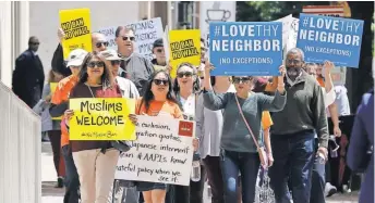  ?? STEVE HELBER, AP ?? Protesters hold signs and marchMonda­y outside the 4th U. S. Circuit Court of Appeals in Richmond, Va., where lawyers for President Trump defended his revised ban on travel.