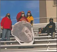  ??  ?? Anna Smith (center left) tries to spot her brother, an El Modena running back, while holding a cutout of him before the game. “I love coming to watch my brother play,” Smith said. “He’s been working hard like everybody else. He’s been really excited to finally get out and play.”