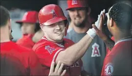  ?? Gail Burton Associated Press ?? MIKE TROUT gets fives in the dugout after hitting a solo homer in the first inning, his 24th of the season and first extra-base hit since June 13.