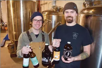  ?? STEVE MacNAULL/The Daily Courier ?? Kettle River Brewing partner Chris Dedinsky, left, and brewmaster Brad Tomlinson pose with beers in front of the new brewing system, which needs a $20,000 crowdfundi­ng campaign to raise the money to outfit the system with a boiler and controls.