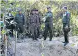  ??  ?? Burmese soldiers beside a mass grave that was discovered earlier this month