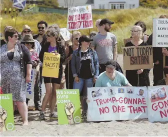  ?? AP PHOTOS ?? ‘NOT ACCEPTABLE’: Protesters, left and above, on a beach near President Trump’s Turnberry golf club in Scotland yesterday and a Greenpeace protester, below, flying a microlight over the resort Friday rally against Trump.