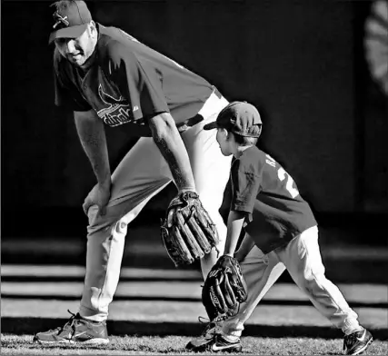  ?? MARK HUMPHREY/ AP ?? St. Louis outfielder John Mabry gives his 5-year-old son J. T. some fielding tips yesterday as the Cardinals get ready for tonight’s Game 6 of the NLCS. It could be the final major league game ever played at Busch Stadium, which is facing the wrecker’s...