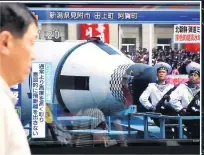  ??  ?? ALARM Citizen in Tokyo, Japan, passes screen showing footage of military parade in Pyongyang yesterday