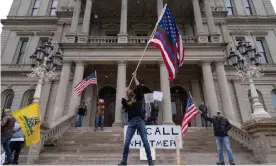  ?? Photograph: Seth Herald/Reuters ?? People hold flags and placards at a protest against the stay-at-home order in Michigan.