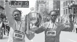  ?? JIM ROGASH/ GETTY IMAGES ?? Lelisa Desisa of Ethiopia, left, winner of the men’s division, and Rita Jeptoo of Kenya, winner of the women’s division, hold a trophy during post- race activities of Monday’s Boston Marathon.