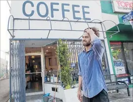  ?? Irfan Khan Los Angeles Times By Ruben Vives ?? JOHN SCHWARZ, co-owner of Weird Wave Coffee, stands in front of the cafe’s shattered glass door. For a peaceful resolution, “we need engagement,” he said.