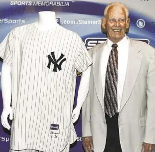  ??  ?? Don Larsen shows off the uniform he last donned on Oct. 8, 1956, the day he pitched the only perfect game in World Series, before it goes to auction. Jeanne Noonan