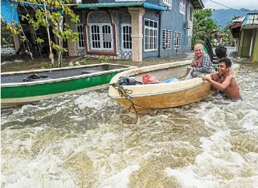  ?? — Zulazhar Sheblee/ The Star ?? Water woes: a family evacuating their flooded home at Kampung Hilir Serian.