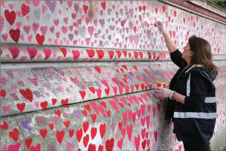  ?? (AP/Kirsty Wiggleswor­th) ?? Volunteer Fran Hall, who lost her husband Steve Mead to covid-19, repaints faded hearts Oct. 15 on the covid-19 memorial wall in Westminste­r in London.