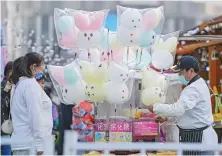  ?? AP ?? A vendor makes cotton candy for his customers during a carnival at a shopping mall in Beijing on Sunday. China has given complete doses of vaccines to about 76 percent of its population as of Oct. 23.