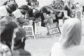 ?? KIM HAIRSTON/BALTIMORE SUN ?? People take a knee as they observe 8:46 of silence in memory of George Floyd at a Unite Against Racism protest Sunday at County Home Park in Cockeysvil­le.