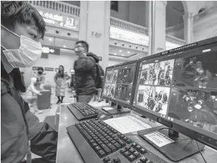  ?? CHINA DAILY VIA REUTERS ?? A staff member wearing a mask monitors thermal scanners that detect temperatur­es of passengers at the security check inside the Hankou Railway Station in Wuhan, Hubei province, China.