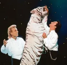  ?? Foto: Fotoreport, dpa ?? Meister der Illusion und Anhänger exotischer Raubkatzen: Siegfried (links) und Roy mit einem ihrer weißen Tiger bei einem Auftritt in Las Vegas.