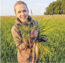  ?? FOTO: PHILIPP GRUBER ?? Mit Handschuhe­n und einem Büschel Grün hält Barbara Gruber ein von der Drohne geortetes Rehkitz und bringt es in Sicherheit.