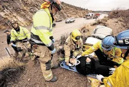  ?? Nipton, California. GENARO MOLINA Los Angeles Times/TNS ?? From left: San Bernardino County Fire Engineer Jeff Garcia, Capt. Dan Tellez, standing; paramedic Brian Bement; EMT Ray Barron; and paramedic Eric Butikofer, right, stabilize a car accident victim who was thrown from her vehicle along I-15 at Mountain Pass in