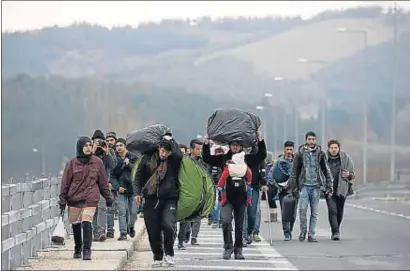  ?? YANNIS BEHRAKIS / REUTERS ?? Un grup de refugiats travessa la frontera entre Grècia i Macedònia, a prop d’Idomeni