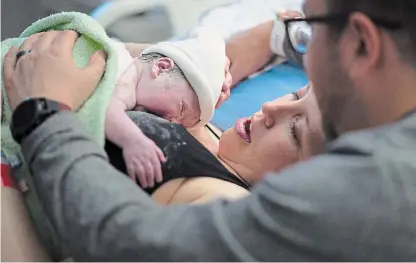  ?? JONATHAN HAYWARD THE CANADIAN PRESS ?? Kate Chong holds her new baby girl Adelynn Susandrea Chong right after delivery as husband Brian looks on at St. Paul's hospital in downtown Vancouver June 14.