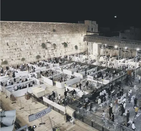  ??  ?? 0 Religious Jews keep social distancing inside dividing cells during the Slichot ( forgivenes­s) prayer on the eve of the Jewish New year, at the Western Wall in Jerusalem