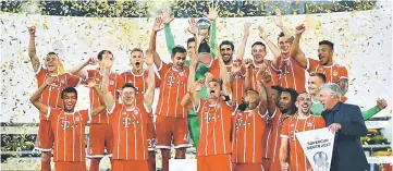  ??  ?? Bayern Munich’s Thomas Muller and his teammates celebrate with the trophy after winning the DFL-Supercup Final. — Reuters photo