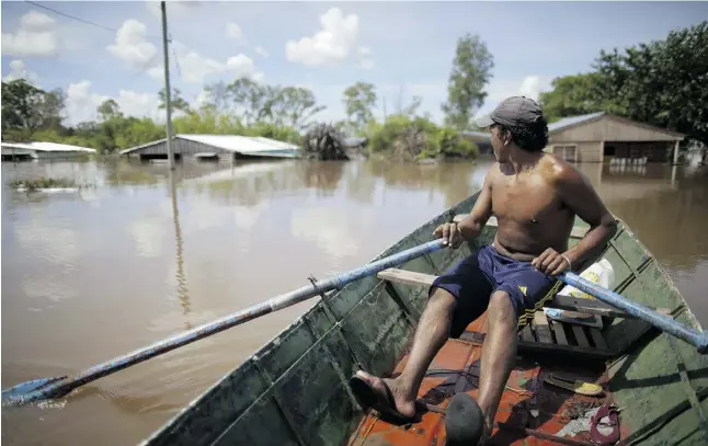  ?? Natacha Pisarenko / The Associated Press ?? A man rows his boat through a flooded street in Concordia, Argentina, on Monday. Some 144,000 were evacuated in neighbouri­ng Paraguay.