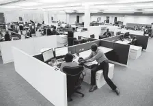  ??  ?? Senior financial analyst Hampton Osir, right, talks with accountant Emorita Ocompo as they work in the new Houston Chronicle building. The open spaces foster a more collaborat­ive atmosphere.