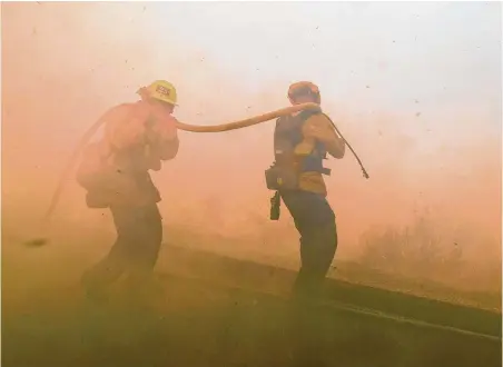  ?? Ringo H.W. Chiu / Associated Press ?? Firefighte­rs battle a brush fire that burned 105 acres Monday in Simi Valley, Calif. Winds remain a concern for spreading fires.